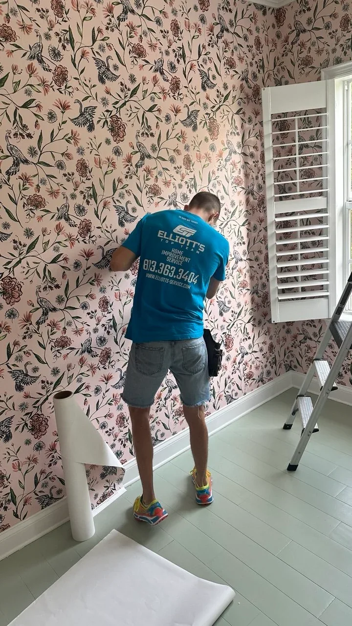 Elliott’s Top Team installer fitting floral wallpaper beside a window